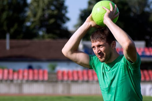 The soccer player is throwing the ball in the playing field.