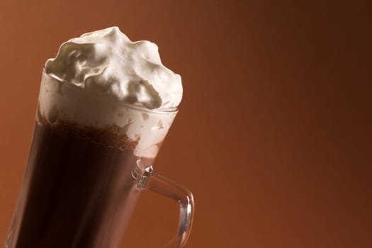 Hot chocolate drink or milkshake with whipped cream on brown background.