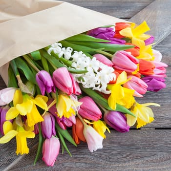 Bouquet of flowers with tulips and daffodils on a rustic wooden background
