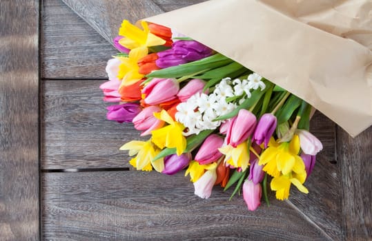 Bouquet of flowers with tulips and daffodils on a rustic wooden background
