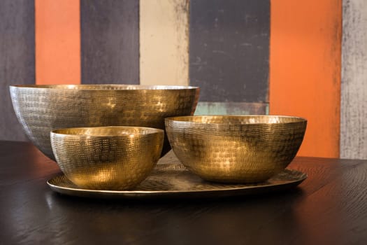 Three empty decorated metal bowls on a table