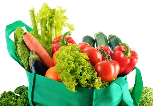 Green shopping bag with variety of fresh organic vegetables isolated on white