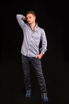Full length portrait of handsome blond young man on dark background
