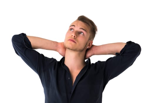 Cool confident blond young man with blue shirt, hands behind head, isolated on white