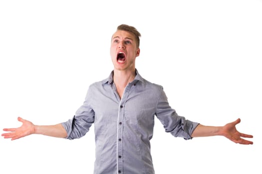 Desperate, angry young man screaming with arms open and looking up