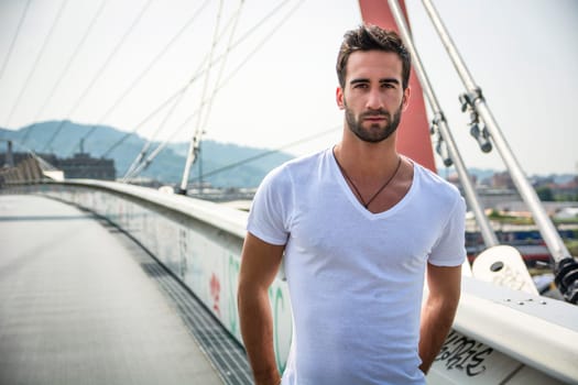 Handsome bearded young man outdoors in urban environment looking at camera