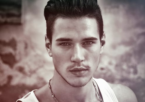 Headshot of attractive black haired young man outside, looking at camera