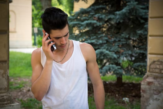 Handsome young man outdoors talking on cell phone in summer