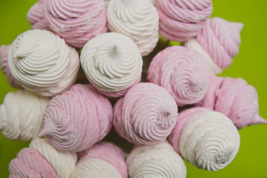 Delicious sweet buffet with homemade pink and white zephyr. Russian marshmallows. On a green background, selective focus