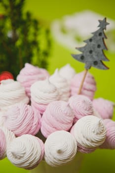Delicious sweet buffet with homemade pink and white zephyr. Russian marshmallows. On a green background, selective focus