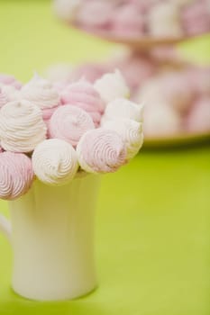 Delicious sweet buffet with homemade pink and white zephyr. Russian marshmallows. On a green background, selective focus
