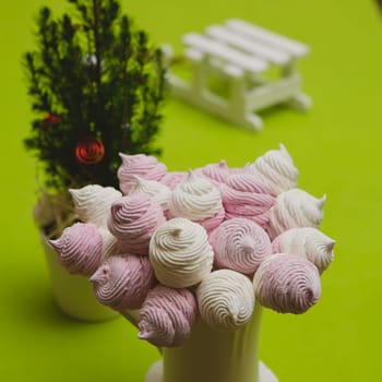 Delicious sweet buffet with homemade pink and white zephyr. Russian marshmallows. On a green background, selective focus