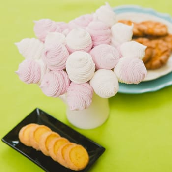 Delicious sweet buffet with homemade pink and white zephyr. Russian marshmallows. On a green background, selective focus