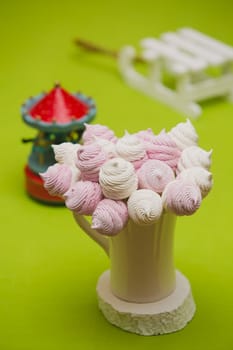 Delicious sweet buffet with homemade pink and white zephyr. Russian marshmallows. On a green background, selective focus