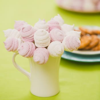 Delicious sweet buffet with homemade pink and white zephyr. Russian marshmallows. On a green background, selective focus