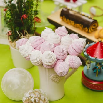 Delicious sweet buffet with homemade pink and white zephyr. Russian marshmallows. On a green background, selective focus