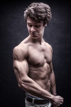 Strong young man looked down dissatisfied to his arm muscles