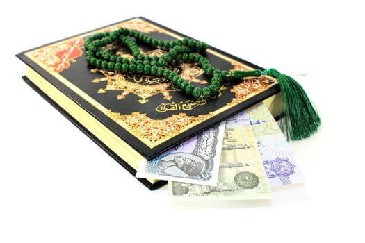 Quran with Egyptian banknotes against a white background