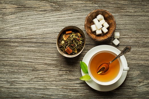 Cup of tea with dry green tea collection with sugar on wooden table