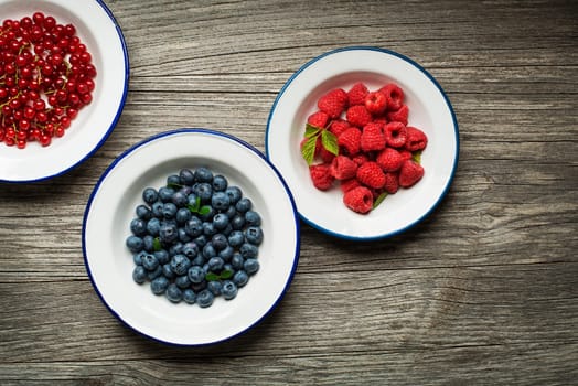 Mix of fresh berries in a bowl on wooden background