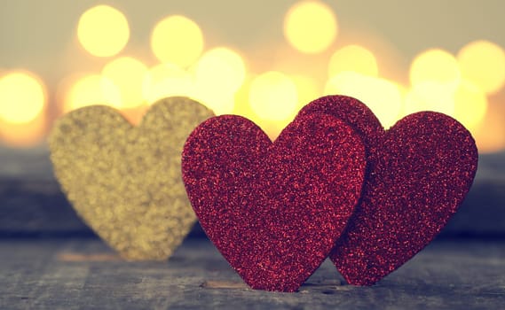 Three glittering heart shapes with blurred lights, love or Valentines Day concept background