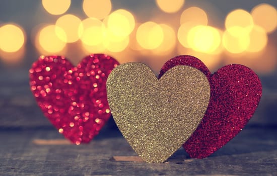 Three glittering heart shapes with blurred lights, love or Valentines Day concept background