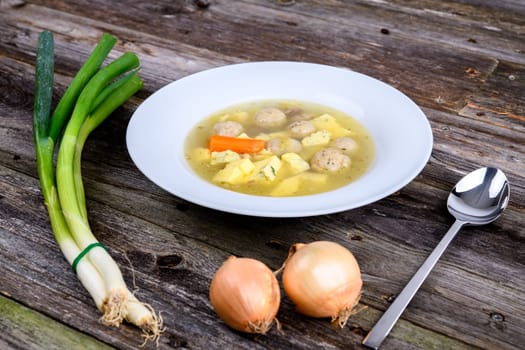 marrow balls soup in white plate with onion on wooden ground