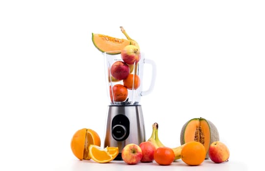 blender with a lot of fruits in front of white background