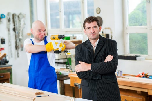 worker aiming at his boss with yellow drilling machine