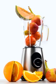 blender with a lot of fruits in front of white background
