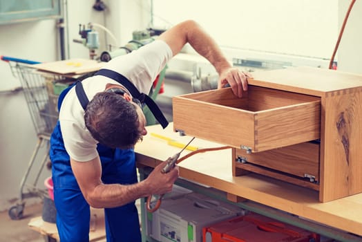 worker in blue dungarees in a carpenter's workshop