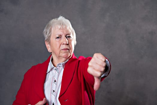 gray hairy elderly woman looking angry and showing thumb down