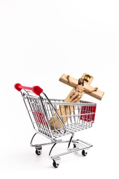 Crucifix in shopping cart. Conceptual representation of commodification of religion, loss of faith, blasphemy. Shallow depth of field.