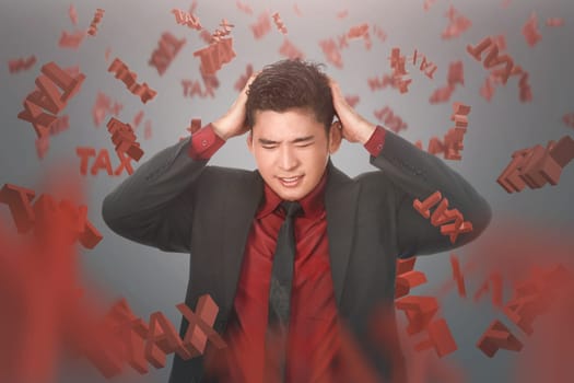 Stressful asian businessman with falling Tax text over black background