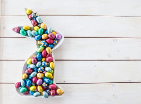 Colorful Easter eggs made of chocolate on white wood background