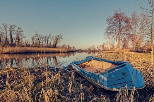 Fishing boat moored on the shore of the lake. Natural landscape.