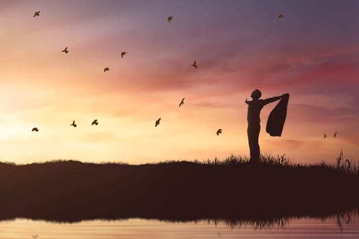 Silhouette of businessman enjoying sun shining with flying birds at sunset