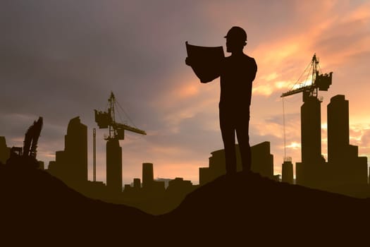 Silhouette of working man standing with his planning paper and crane in construction site at sunset