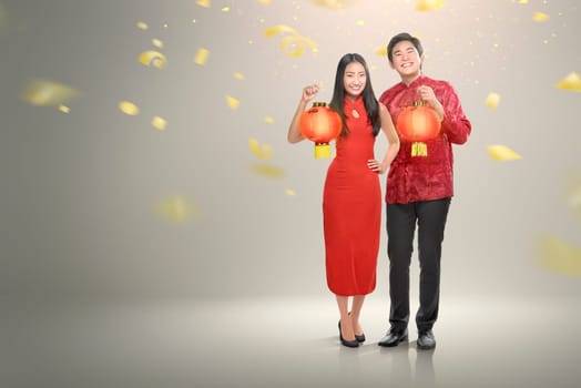 Happy chinese couple in cheongsam clothes holding red lanterns with confetti background. Happy Chinese New Year