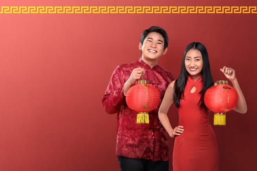 Beautiful chinese couple holding red lanterns on red background. Happy Chinese New Year
