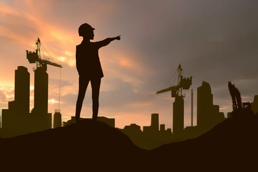 Silhouette of engineering woman with hard hat pointing project construction site at sunset background