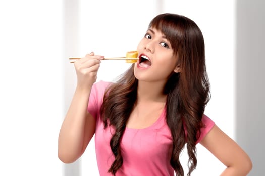Beautiful asian woman eating sushi using chopsticks on the home
