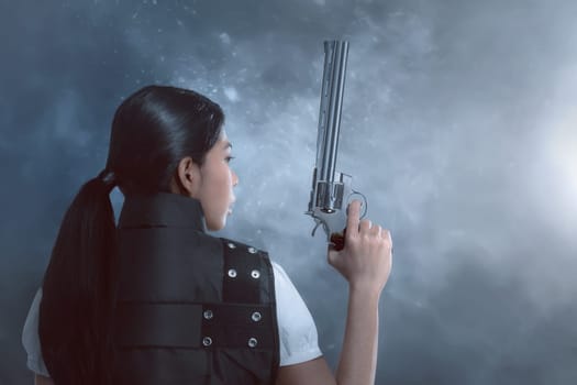 Back view of asian woman with police uniform holding guns on dark background
