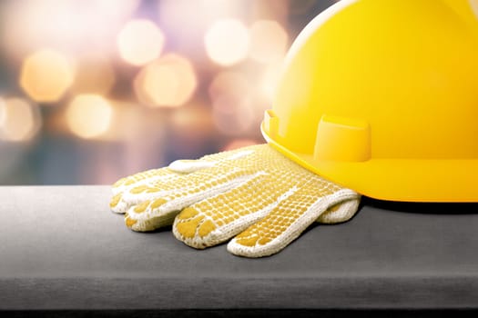 Safety helmet and gloves on the table with blur lights background