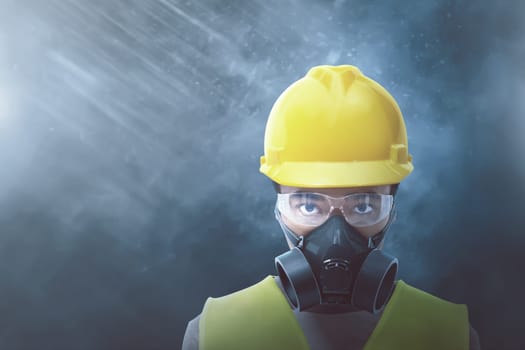 Young asian worker with yellow helmet and protective mask over black background
