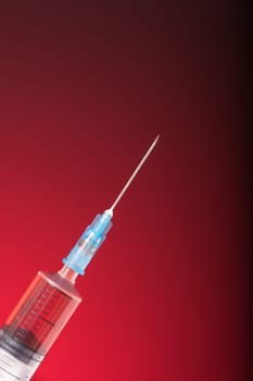 Isolated medical syringe on red, dark background