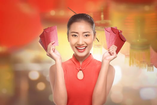 Young chinese woman in a cheongsam clothes with red envelope over lantern background