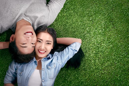 Top view of asian couple in love lying on a green grass at outdoor