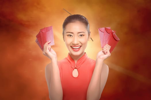 Happy chinese woman with cheongsam holding red envelopes on red background