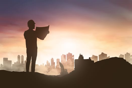 Silhouette of engineer man looking his blueprint in construction site at sunset